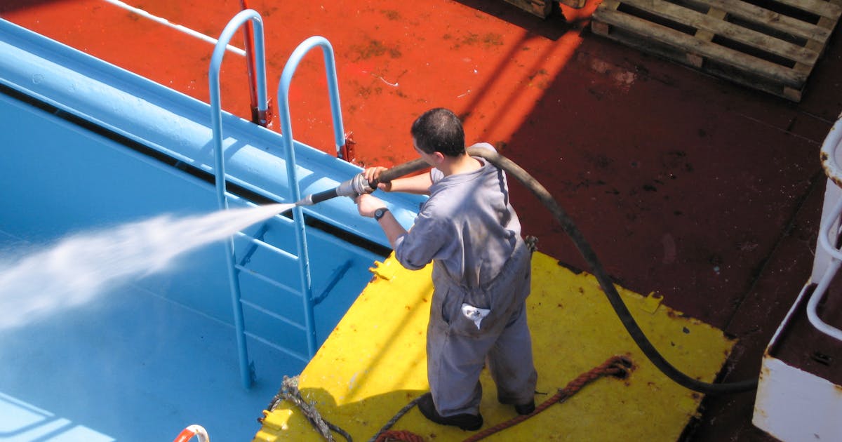 Person pressure washing a wooden deck
